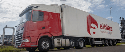 Rode en witte Alblas vrachtwagen rijdend op een industrieterrein.