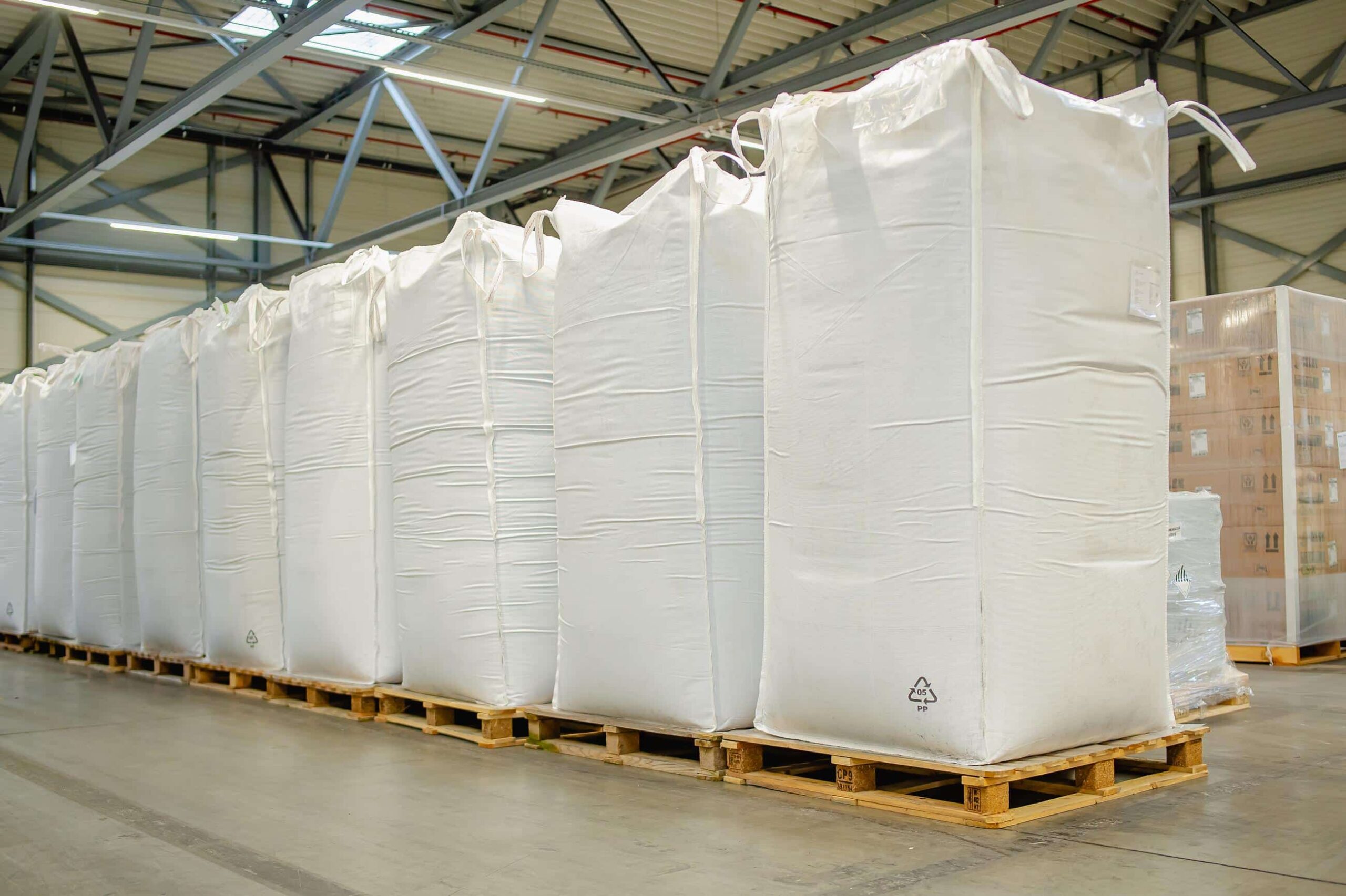 Grote witte bulkzakken op pallets klaar voor distributie in het magazijn van Alblas Logistics.
