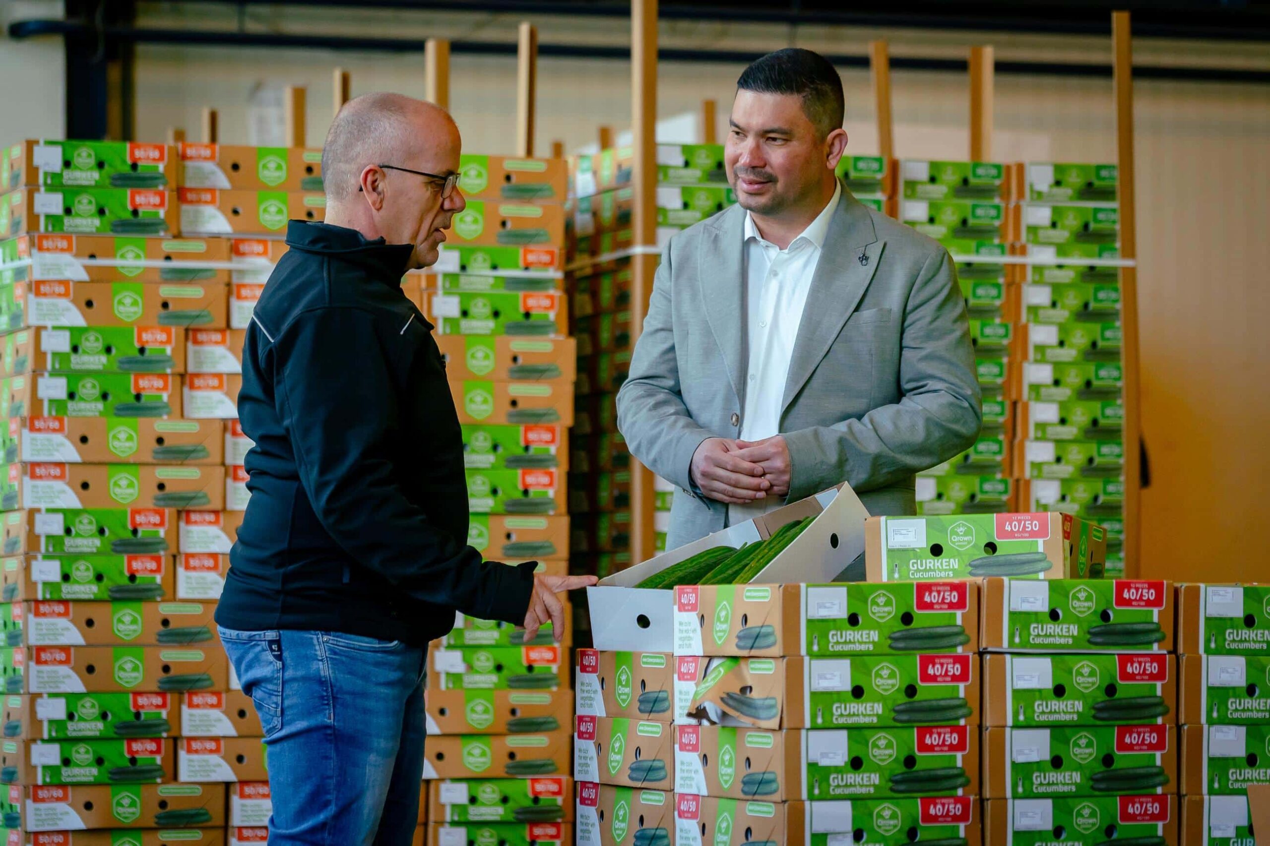 Twee mannen inspecteren versproducten in een logistiek centrum tussen gestapelde AGF-dozen.
