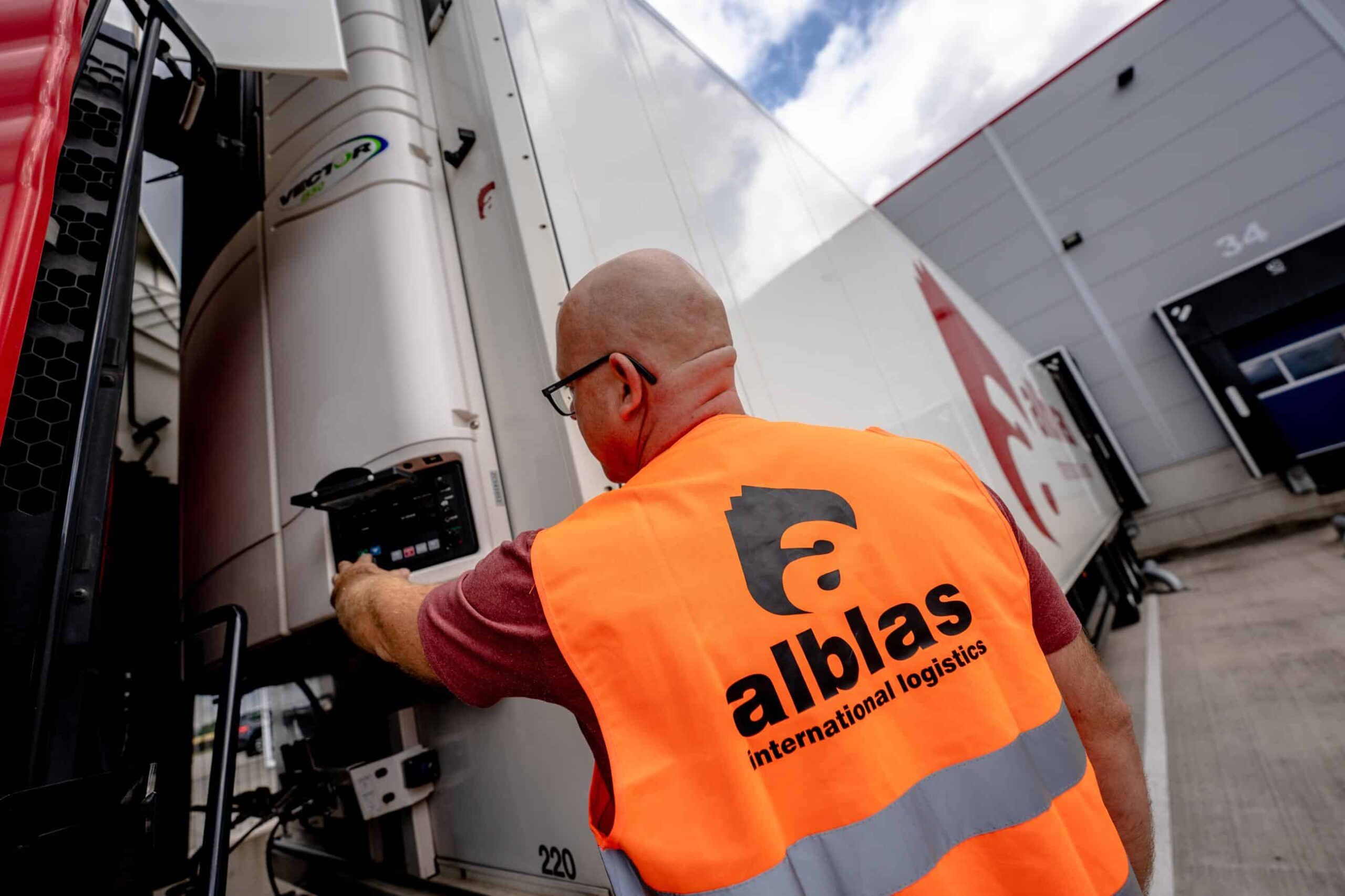 Nieuwe medewerker van Alblas in veiligheidsvest bij trailer tijdens inspectie.