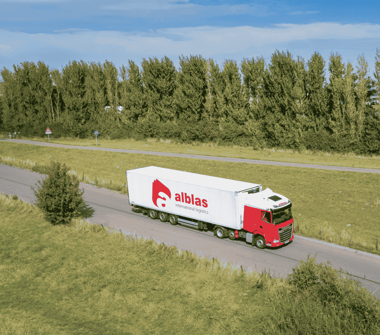 Alblas vrachtwagen met oplegger en bedrijfslogo, rijdt over de weg voor transportdiensten.